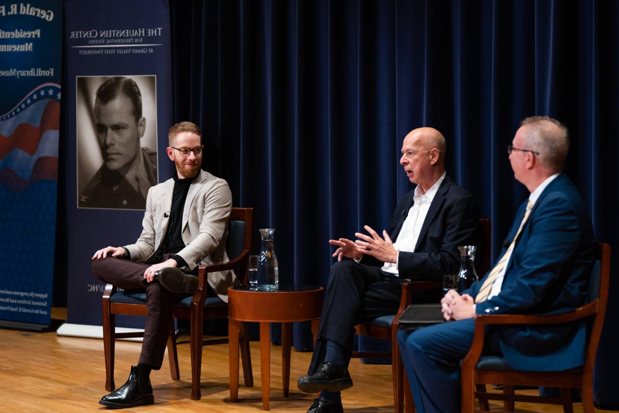 three people talking on a stage